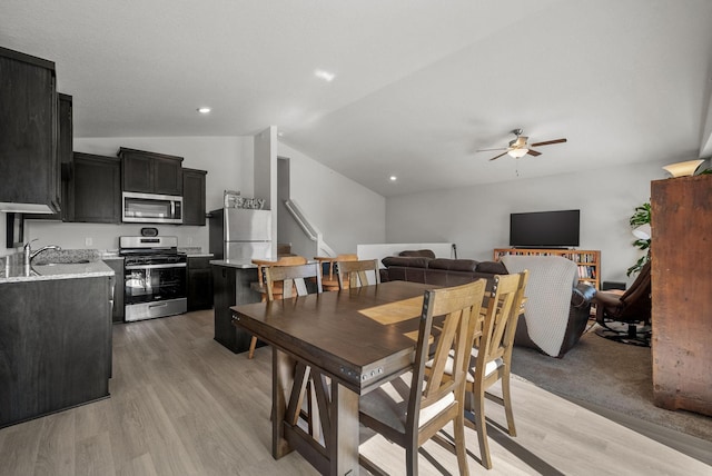 dining room with light wood-style floors, vaulted ceiling, stairway, and ceiling fan