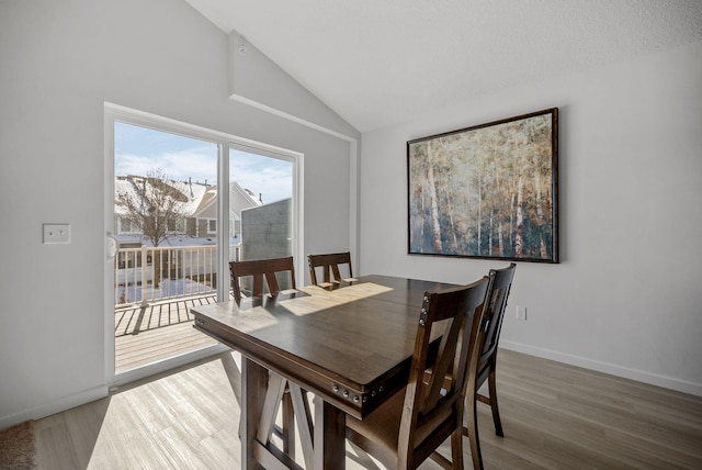 dining space featuring lofted ceiling, wood finished floors, and baseboards