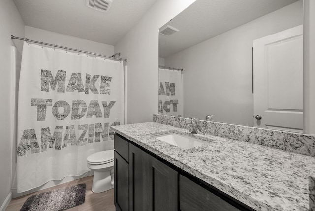 bathroom featuring toilet, wood finished floors, vanity, and visible vents