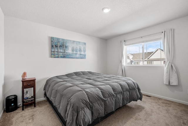 bedroom featuring light carpet, baseboards, and a textured ceiling