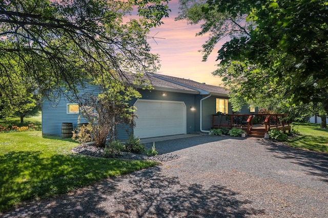 view of front of house with an attached garage, a yard, a deck, and gravel driveway