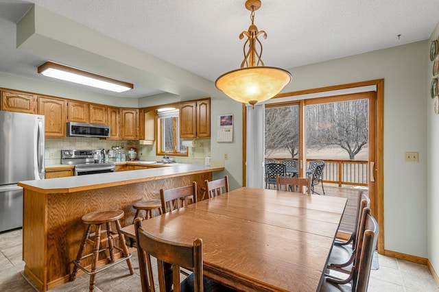 dining room featuring light tile patterned floors, baseboards, and a textured ceiling