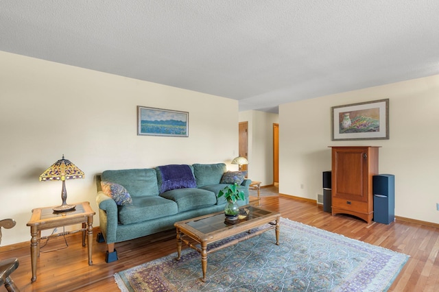 living area with light wood-style floors, a textured ceiling, and baseboards