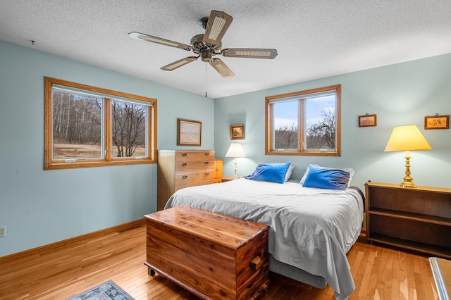 bedroom featuring a textured ceiling, ceiling fan, baseboards, and light wood-style floors