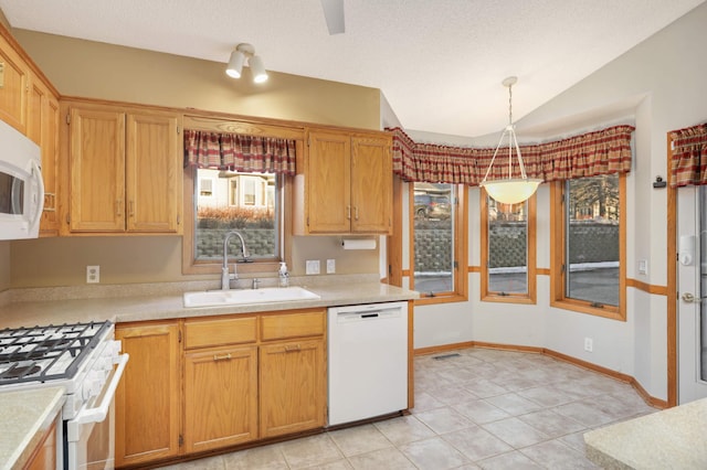 kitchen featuring white appliances, vaulted ceiling, light countertops, and a sink