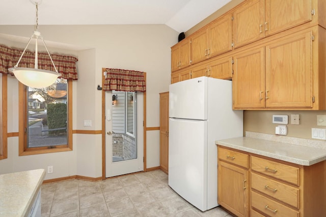 kitchen featuring freestanding refrigerator, light countertops, vaulted ceiling, and baseboards