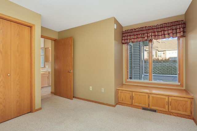 interior space featuring baseboards, visible vents, and light colored carpet