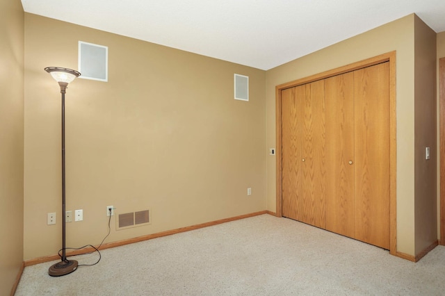 unfurnished bedroom with carpet floors, baseboards, visible vents, and a closet