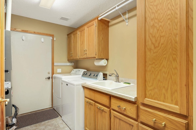 washroom featuring cabinet space, visible vents, a sink, a textured ceiling, and independent washer and dryer