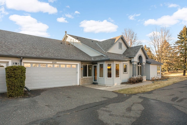 view of front of home featuring aphalt driveway, a shingled roof, and a garage