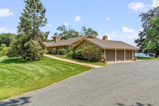 view of front of property with a garage, gravel driveway, a chimney, and a front lawn