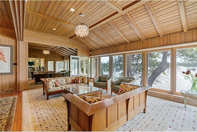 living area featuring lofted ceiling, wood walls, visible vents, and an inviting chandelier