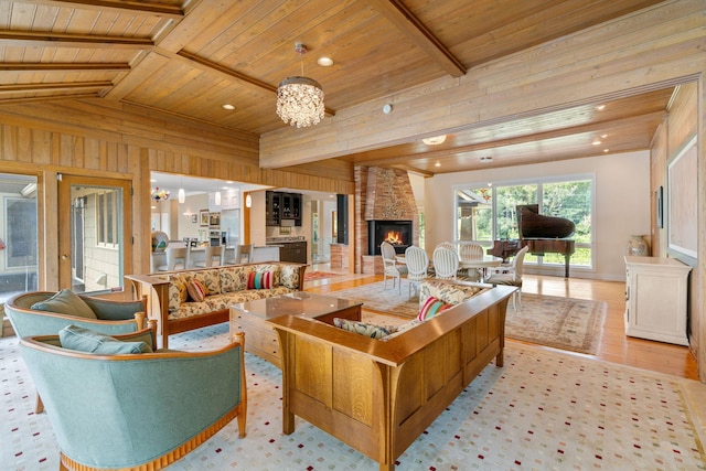 living area featuring wooden ceiling, a stone fireplace, lofted ceiling with beams, and an inviting chandelier