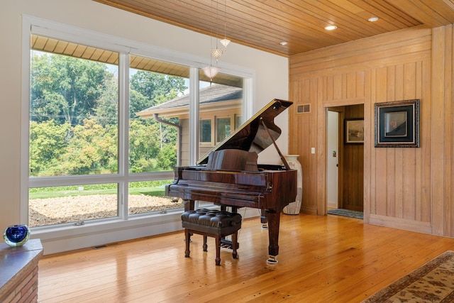 living area featuring wood ceiling, hardwood / wood-style flooring, visible vents, and wooden walls