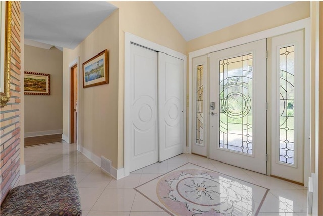 entryway with lofted ceiling, light tile patterned floors, visible vents, and baseboards