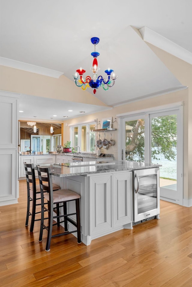 bar featuring light wood-type flooring, an inviting chandelier, beverage cooler, and ornamental molding