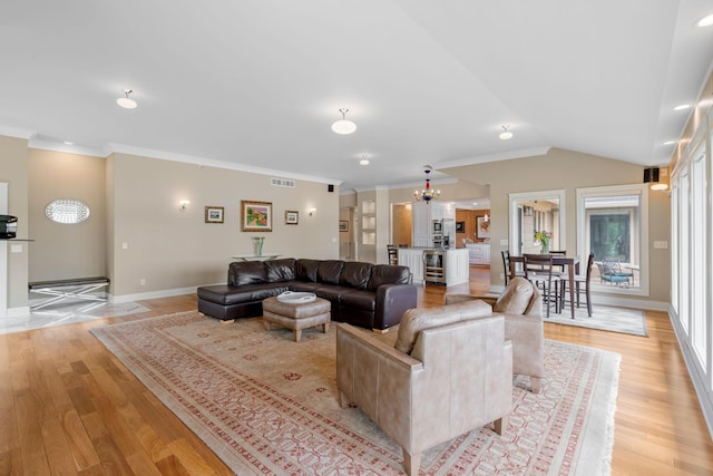 living area featuring lofted ceiling, visible vents, baseboards, light wood-style floors, and ornamental molding