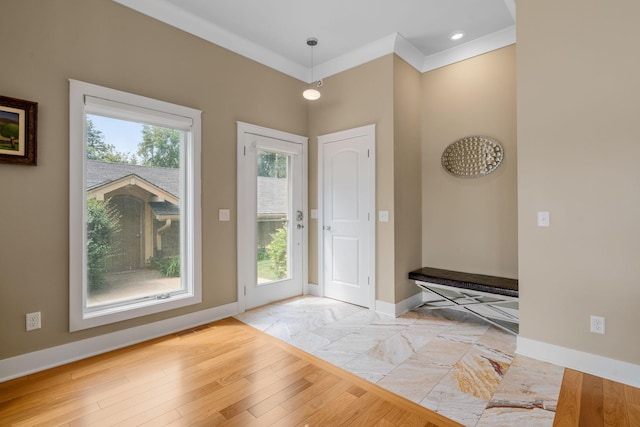 foyer entrance with visible vents, crown molding, light wood-style flooring, and baseboards