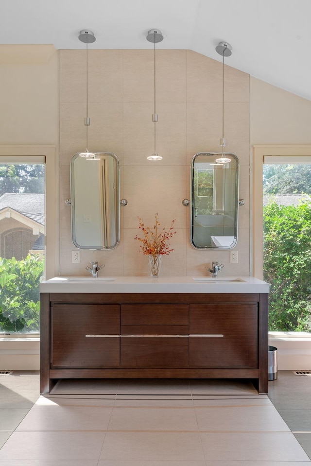 full bathroom with vaulted ceiling, double vanity, a sink, and visible vents