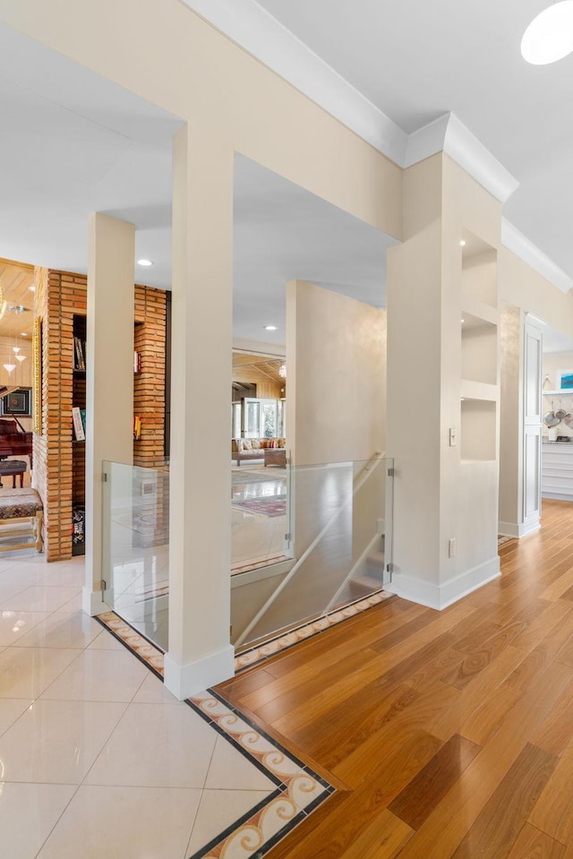 interior space featuring built in features, ornamental molding, an upstairs landing, wood finished floors, and baseboards