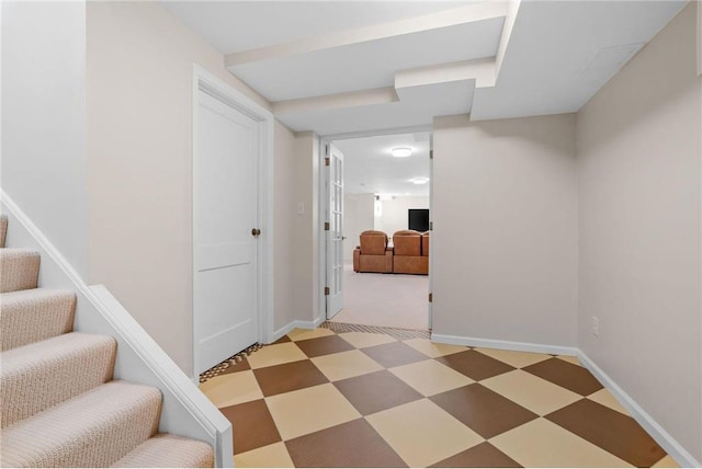 corridor with baseboards, light floors, and stairs