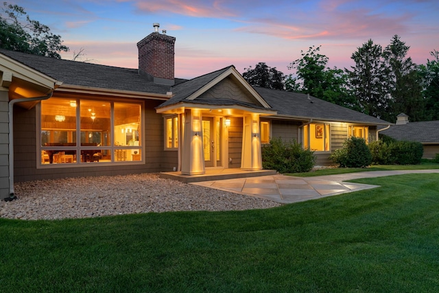 back of property featuring a lawn and a chimney