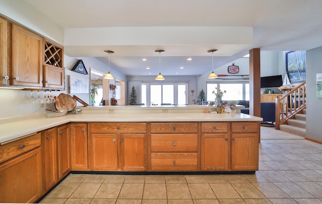 kitchen with a peninsula, brown cabinets, pendant lighting, and light countertops