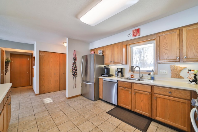 kitchen featuring brown cabinets, light tile patterned floors, light countertops, appliances with stainless steel finishes, and a sink