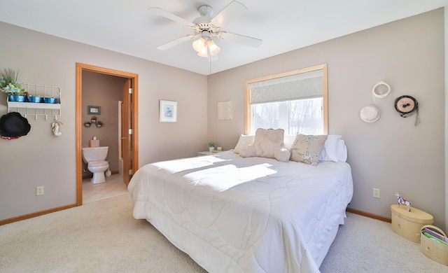 bedroom with light colored carpet, ceiling fan, baseboards, and ensuite bathroom