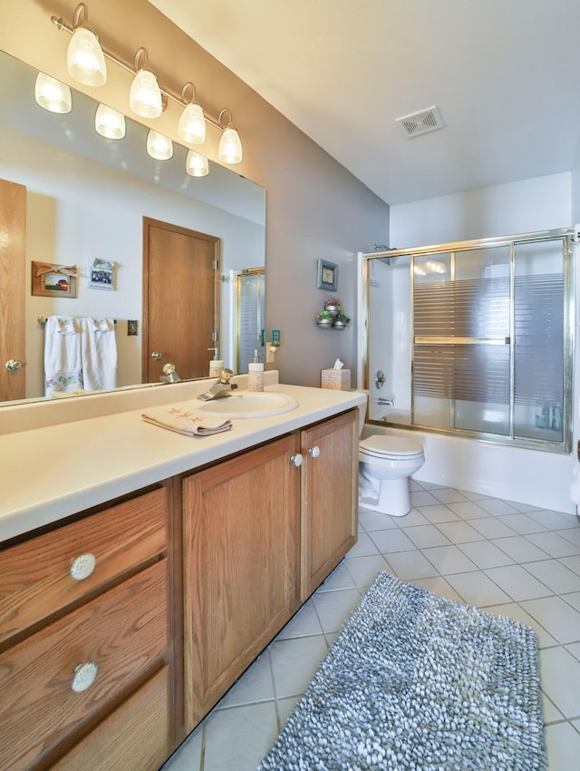 full bathroom with bath / shower combo with glass door, visible vents, toilet, vanity, and tile patterned flooring