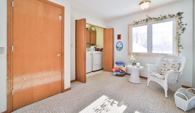 living area with light colored carpet, baseboards, and separate washer and dryer