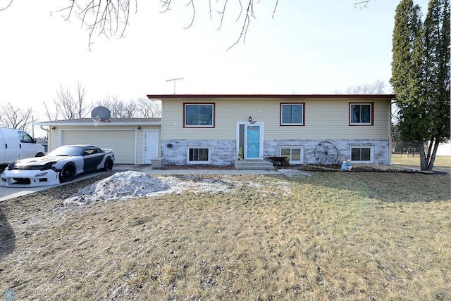 raised ranch featuring entry steps, concrete driveway, a garage, and a front lawn