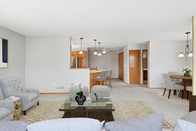 living area with light carpet, visible vents, baseboards, and an inviting chandelier