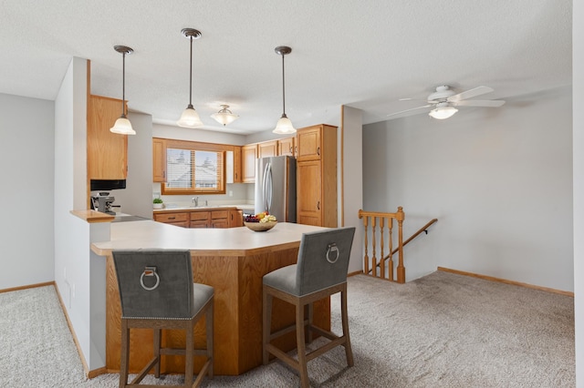 kitchen with light carpet, light countertops, freestanding refrigerator, and a sink