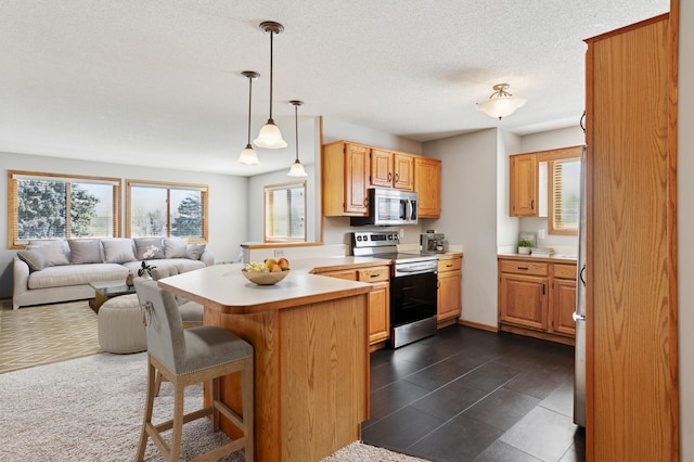 kitchen with a breakfast bar area, a peninsula, light countertops, appliances with stainless steel finishes, and open floor plan