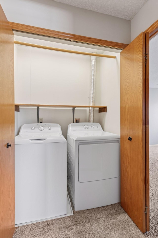 washroom with a textured ceiling, laundry area, carpet, and washer and clothes dryer