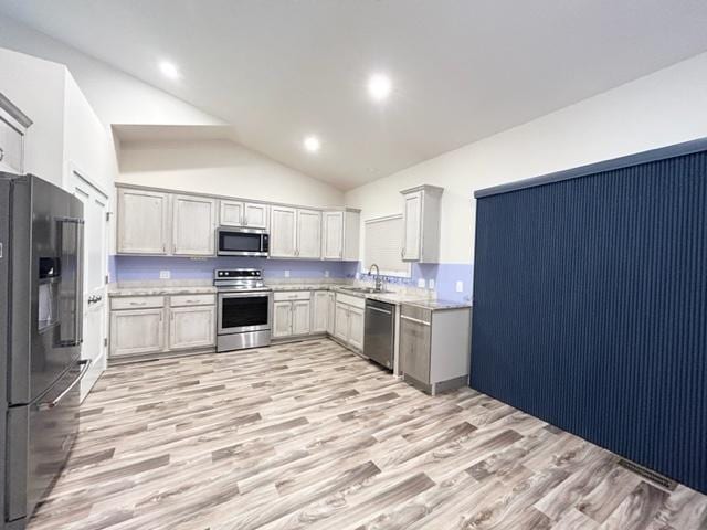 kitchen with light wood finished floors, recessed lighting, appliances with stainless steel finishes, a sink, and high vaulted ceiling