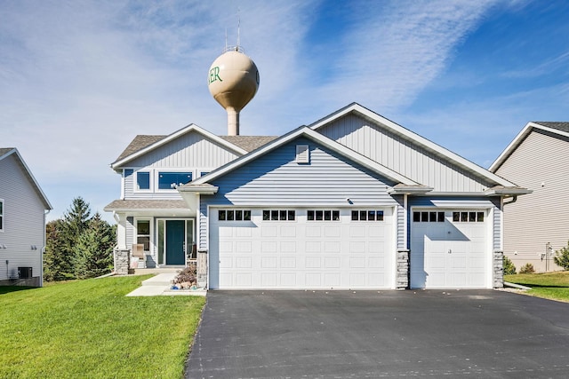 view of front of home with aphalt driveway, an attached garage, board and batten siding, a front yard, and stone siding