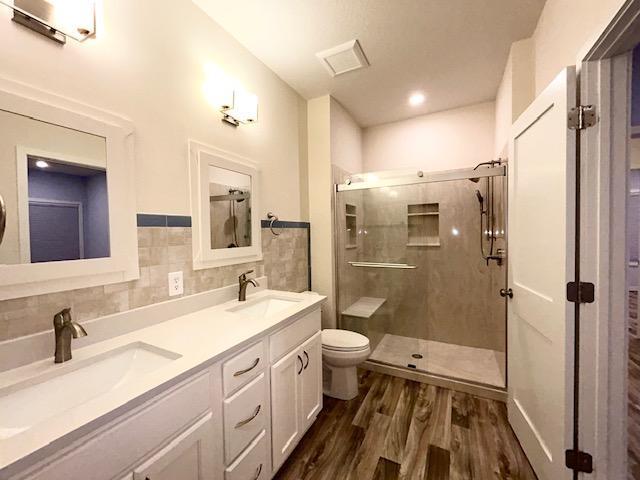 full bathroom with wood finished floors, a stall shower, a sink, and tile walls