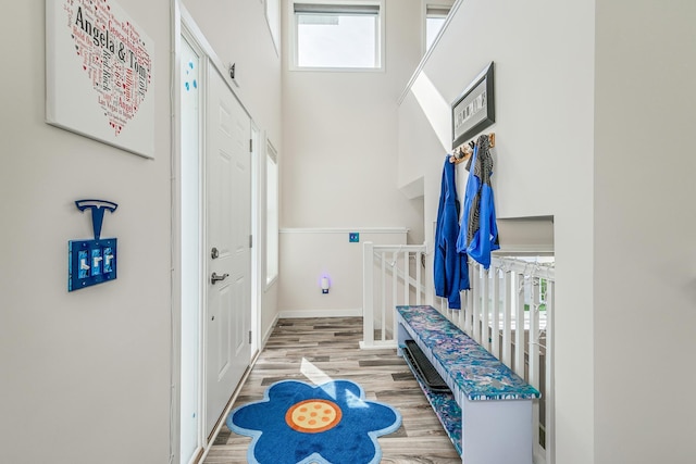 mudroom featuring baseboards, a high ceiling, and wood finished floors