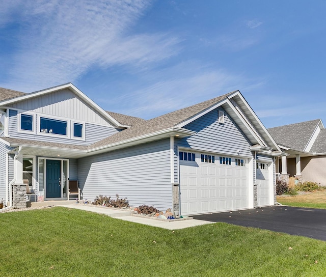 view of front of home featuring a garage, a front yard, roof with shingles, and driveway