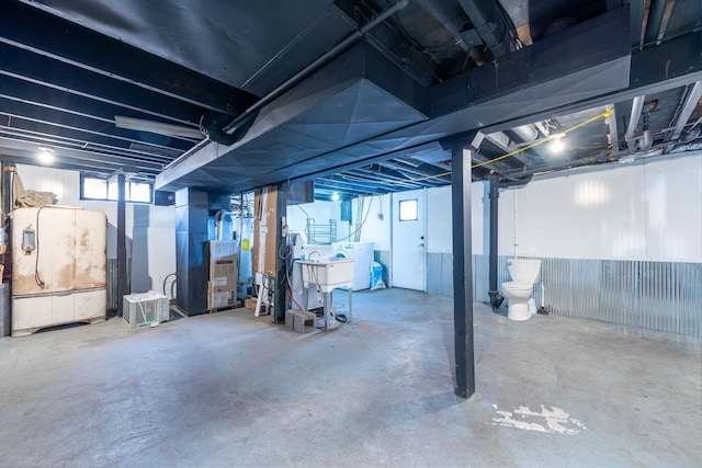 basement featuring washer / dryer, sink, and heating unit