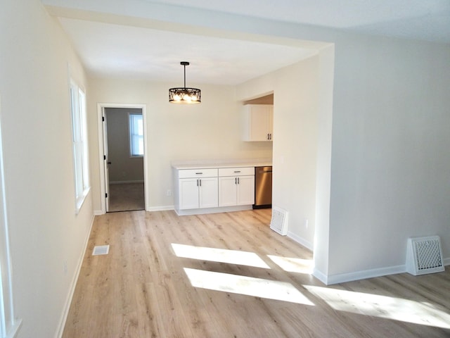 unfurnished dining area featuring light wood-type flooring and an inviting chandelier