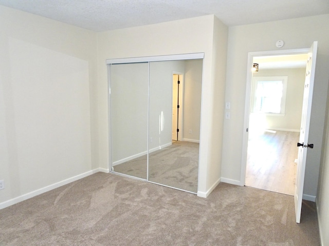 unfurnished bedroom with a closet and light colored carpet