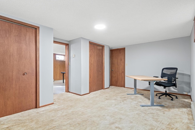 home office with baseboards, a textured ceiling, and light colored carpet