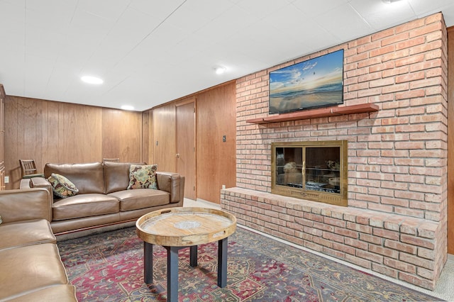 living room featuring a brick fireplace, recessed lighting, and wood walls