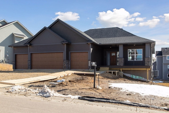 craftsman-style house with stone siding, covered porch, a shingled roof, and a garage