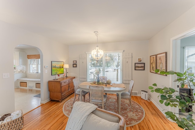 dining room with a healthy amount of sunlight, a chandelier, and light hardwood / wood-style floors