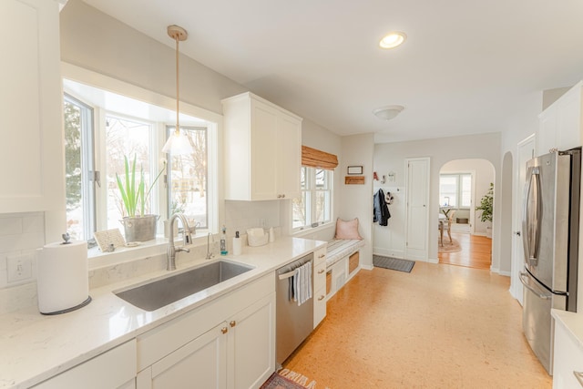 kitchen featuring sink, white cabinetry, stainless steel appliances, and decorative light fixtures