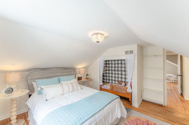 bedroom featuring light hardwood / wood-style floors and lofted ceiling